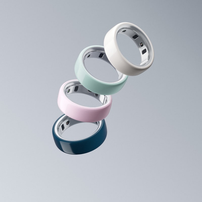 Oura Ring Gen 3 in silver, shown on a flat surface next to its charging dock